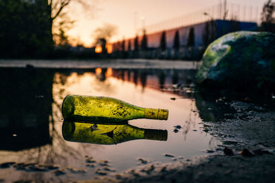 Reflection of bottle on puddle at road