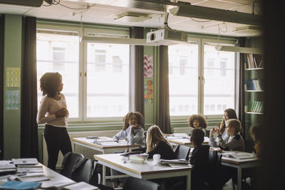 Students and teacher discussing during lecture in classroom