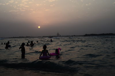 People enjoying at beach during sunset