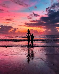 Silhouette people on beach against sky during sunset