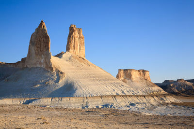 Rock formations in desert against clear blue sky