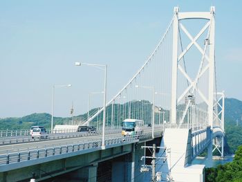 Suspension bridge in city against clear sky