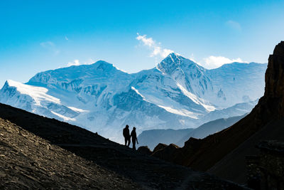 Silhouette people standing against snowcapped mountains