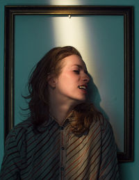 Mid adult woman standing against picture frame on wall