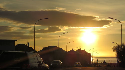 Cars on road against dramatic sky during sunset