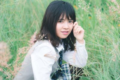 Portrait of beautiful young woman by plants on field 