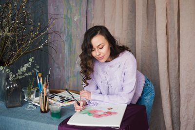 Woman looking away while sitting on table