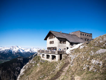 Houses by mountain against clear blue sky