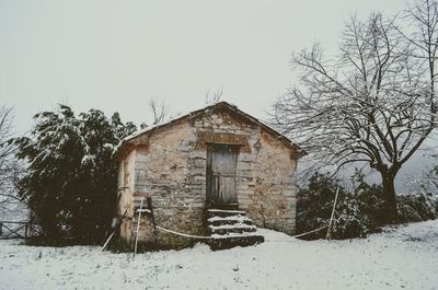 House on snow covered field against sky