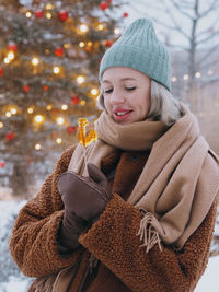 Young stylish smiling woman eating rooster shaped lollipop on a christmas market.