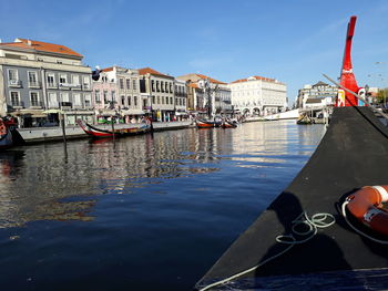 Boats moored in canal by buildings in city against sky