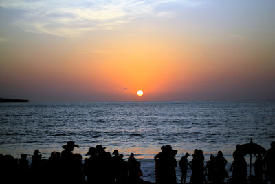 Silhouette people on beach against sky during sunset