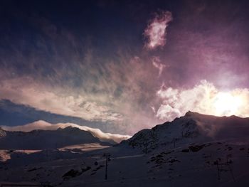 Low angle view of snowcapped mountains against cloudy sky