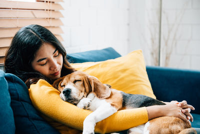 Young woman with dog sitting on sofa at home