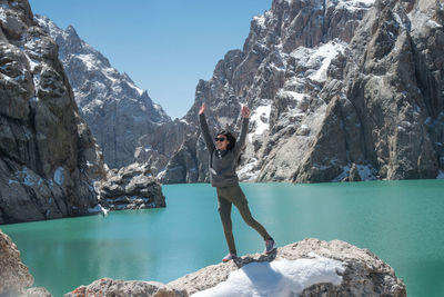 Full length of woman standing on rock by lake