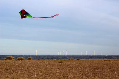 Kite flying over lake against sky