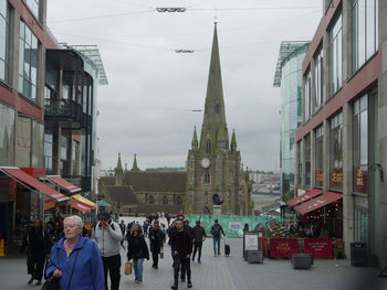 People walking on street in city against sky