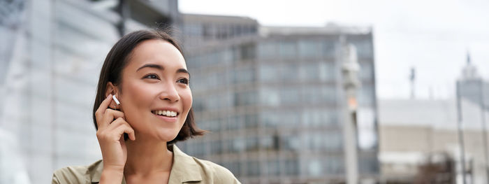 Portrait of young woman standing against buildings