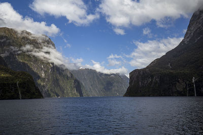 Scenic view of sea by mountains against sky