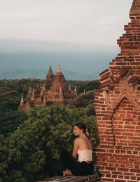 Rear view of woman sitting outside building against sky