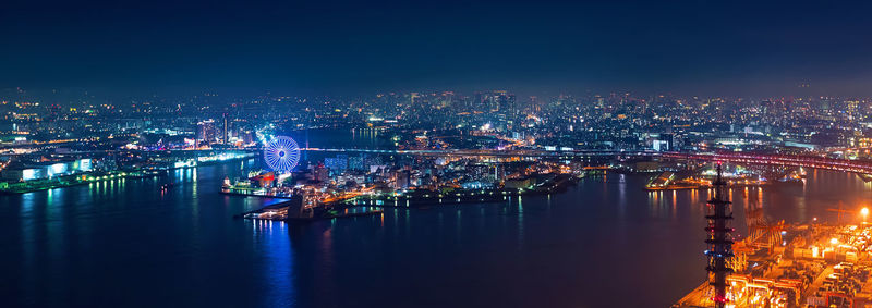 Illuminated buildings by river in city at night