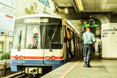 Man standing on train at railroad station