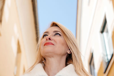 Close-up of a poised older woman gazing up with a backdrop of a clear sky