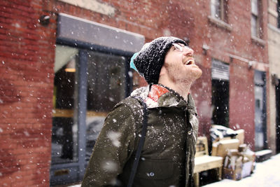 Happy man enjoying snow in city