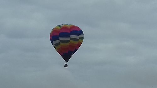 Low angle view of balloons against cloudy sky