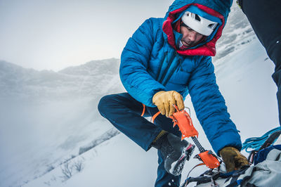 Man holding umbrella on snow against mountains