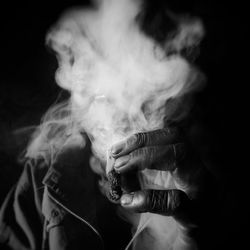 Close-up of man smoking over black background