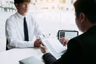 Midsection of man and woman holding mobile phone while sitting on table