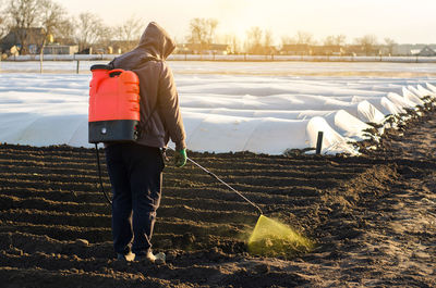 The farmer treats the field from weeds and grass for growing potatoes. use chemicals in agriculture