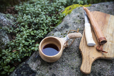 Cup of tea kept by knife with cutting board on rock