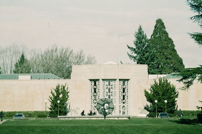 Trees and plants on field against building