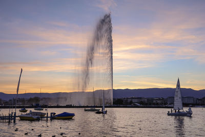 Sailboats in sea against sky during sunset