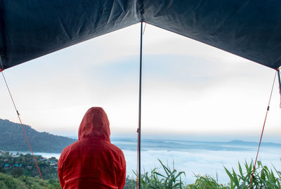 Rear view of man in tent against sky