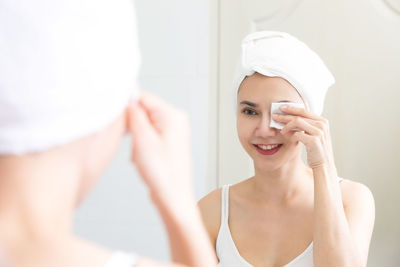 Reflection beautiful woman removing make-up in mirror