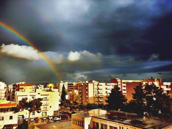 Rainbow over buildings in city against sky