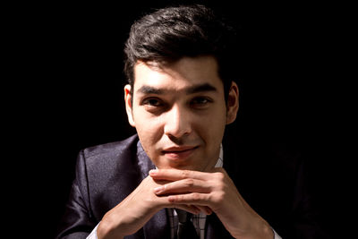 Portrait of young businessman against black background