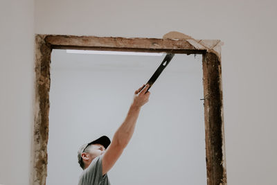 A man working with a crowbar in a doorway.