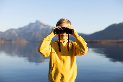 Boy in yellow hooded shirt looking through binocular