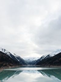 Mountains by lake against cloudy sky