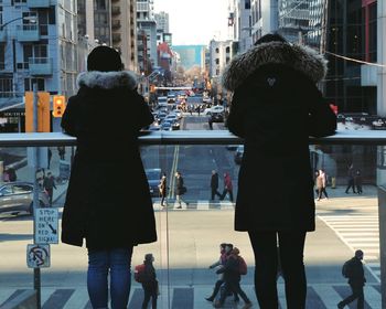 Rear view of people walking on street in city