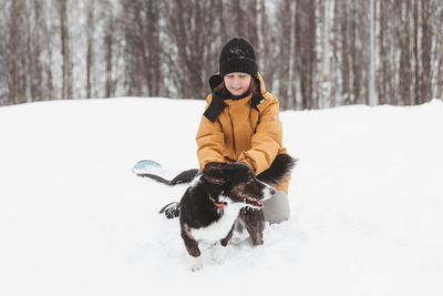 A girl plays with a corgi dog in a winter park