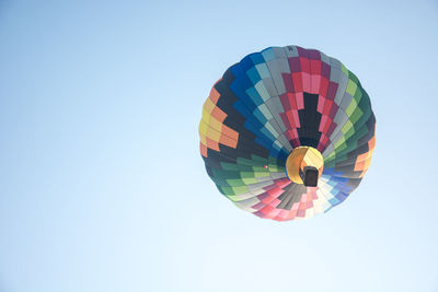 Low angle view of multi colored hot air balloon flying against clear sky