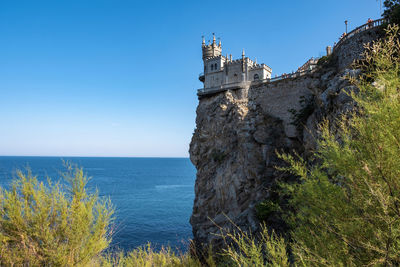 Building by sea against blue sky