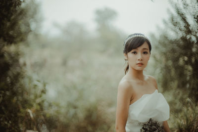 Portrait of woman holding bouquet while in forest