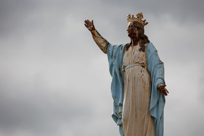 Low angle view of mary statue against sky