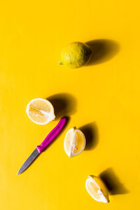 Directly above shot of lemons with knife on yellow background